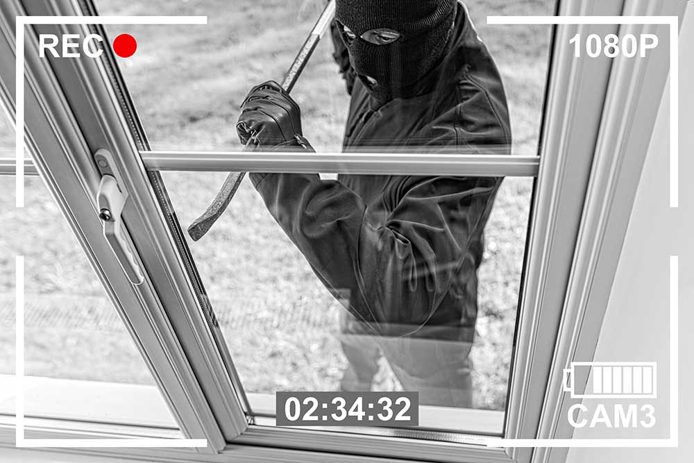 Surveillance footage shows a masked person in dark clothing prying open a window—highlighting why Estates-in-Nevada-From-Modern-Security-Threats-1 is essential for film set security. Timer and camera icons are visible on screen.