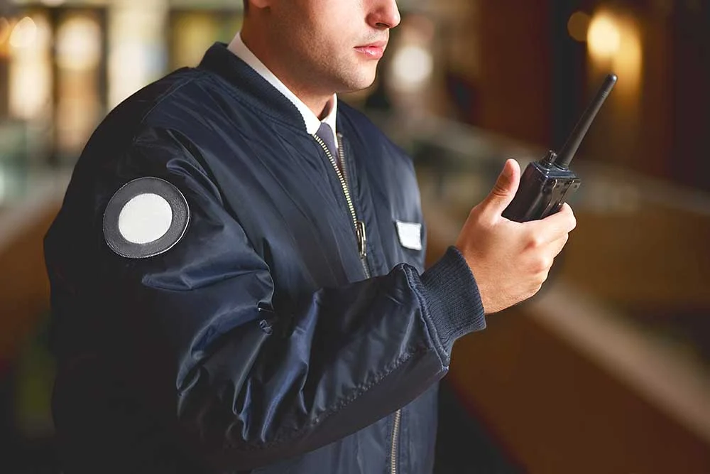 A security guard in a dark jacket speaks into a walkie-talkie, showcasing the professionalism of Executive Protection & Bodyguards in Las Vegas, as seen in security-image-1 from Alexios Security Solutions.