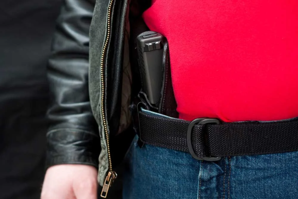 In ccw-training-image-2, an individual in a red shirt, blue jeans, and black leather jacket carries a holstered handgun, highlighting the value of Las Vegas firearm safety training.