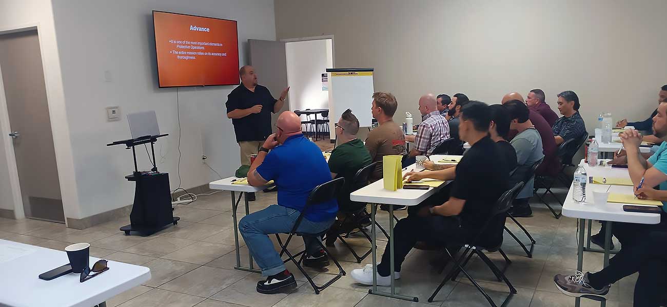 A man presents “Behavioral-Intelligence–1” to a classroom group seated at tables, with “Advance” on the screen as attendees listen attentively, taking notes with folders and drinks on the tables. Antonio Guadagni presents "Behavioral-Intelligence--1" to a classroom group seated at tables, with "Advance" on the screen as attendees listen attentively, taking notes with folders and drinks on the tables.