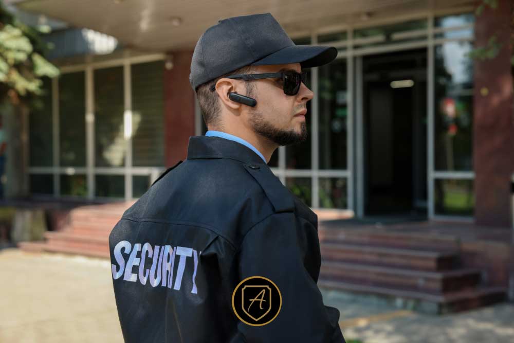 A security guard in a black uniform labeled "SECURITY" stands alert outside a building, providing executive protection—an example from The-Real-Value-of-Uniformed-Security-Guards-for-Nevada-Businesses-3. | Executive Protection & Bodyguards in Las Vegas | Alexios